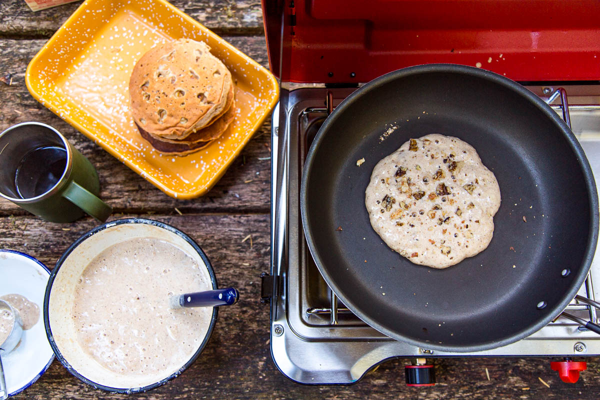 An overhead view of pancake in a skillet on a camp stove.