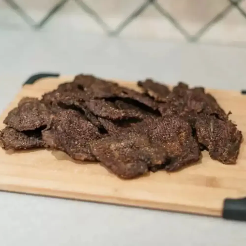A pile of beef jerky on a wood cutting board