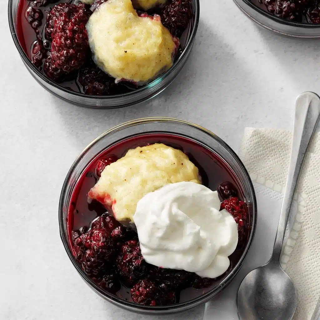 Bowls with blackberry filling, dumplings, and whipped cream.