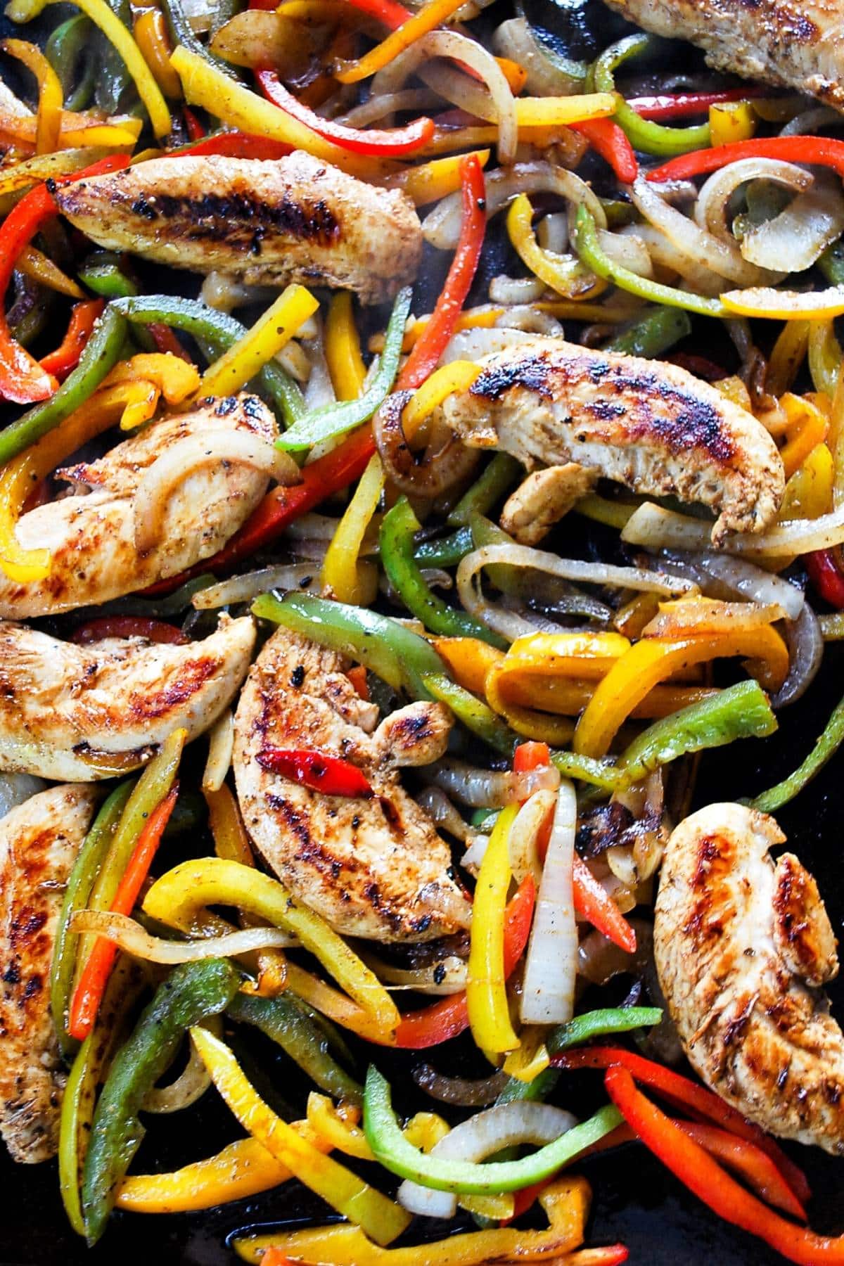 Chicken, bell peppers, and onions on a Blackstone grill.