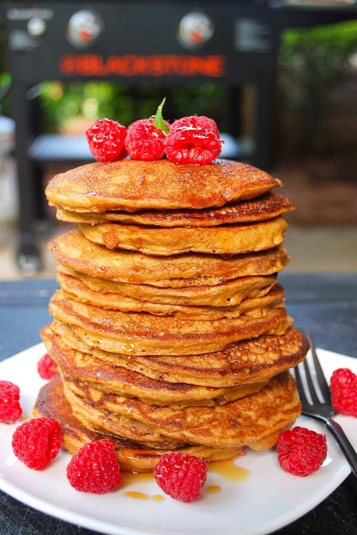 A stack of pancakes topped with raspberries.