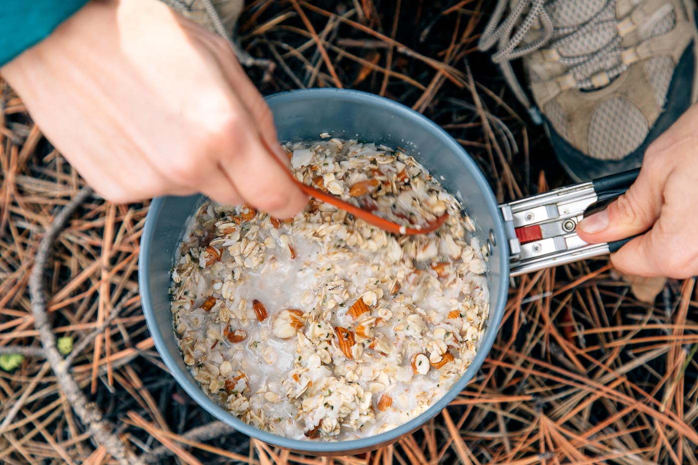 Woman stirring coconut oatmeal in a backpacking pot.