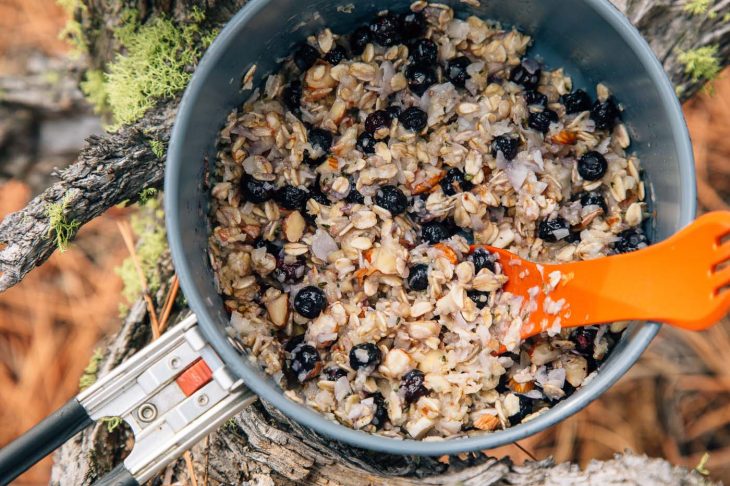 Blueberry coconut oatmeal in a backpacking pot set on a natural background.