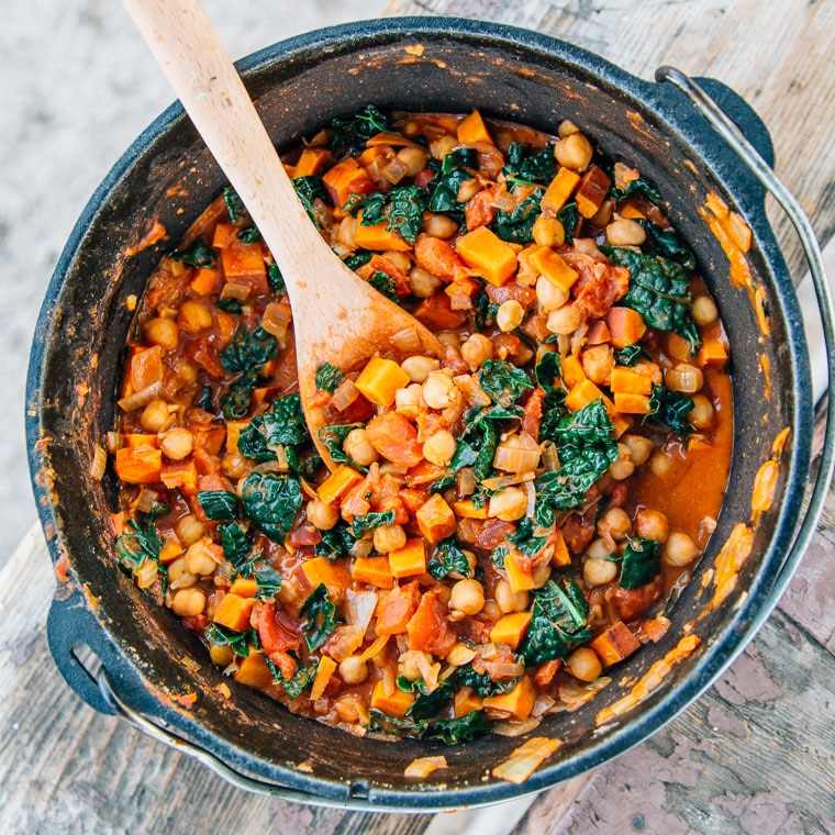 Sweet potato peanut stew in a dutch oven with a wooden spoon