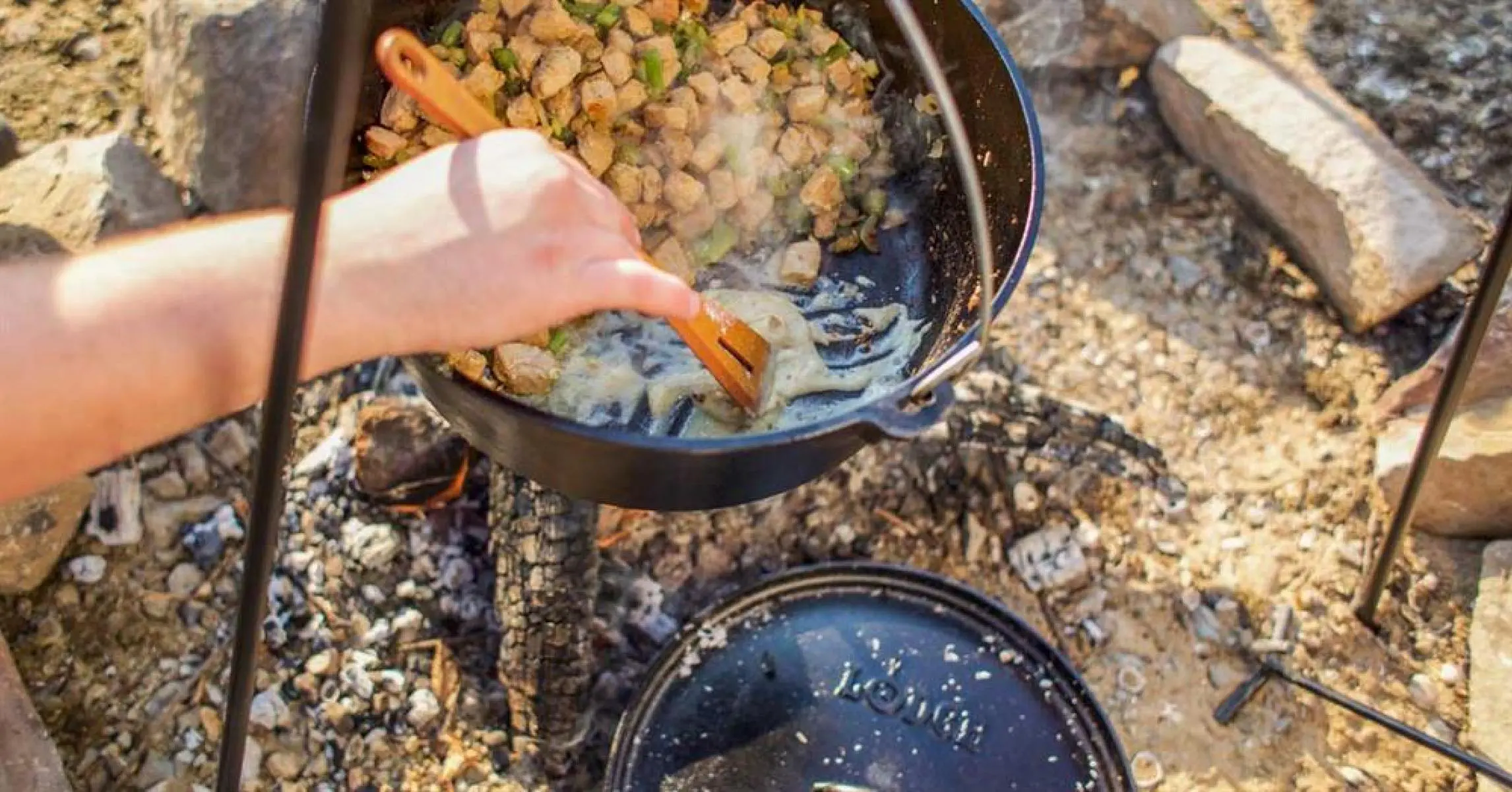 Stirring chile verde in a Dutch oven hanging over a campfire