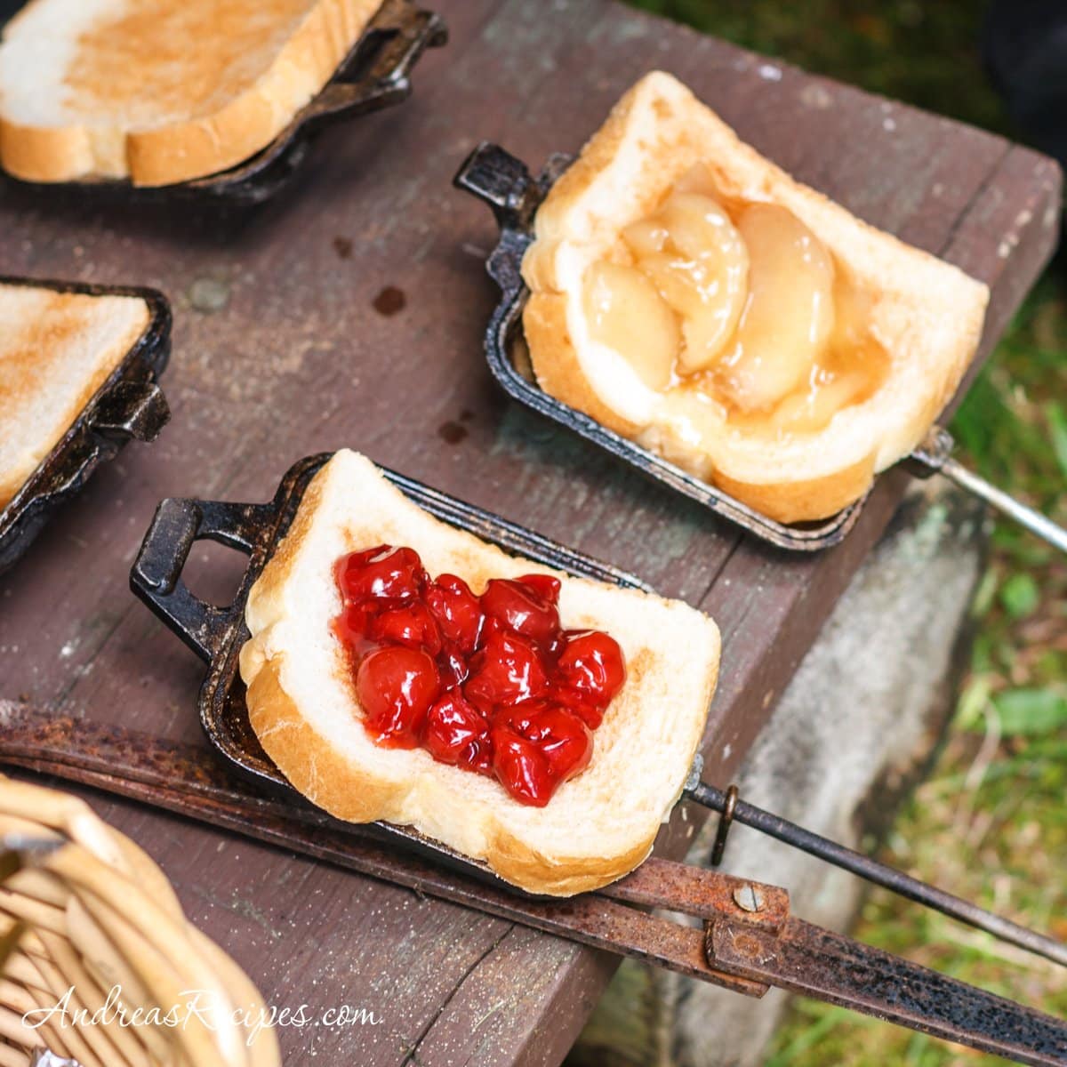 Slices of bread topped with fruit in pie irons.