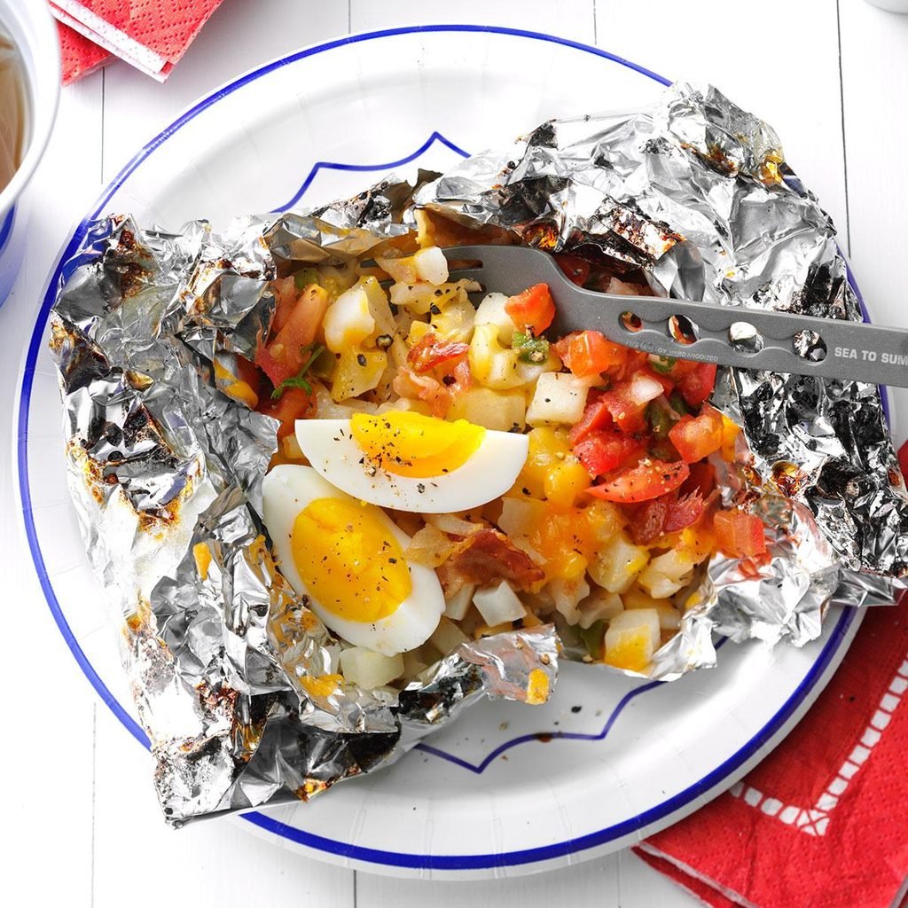A foil packet containing potatoes, eggs, and tomatoes.