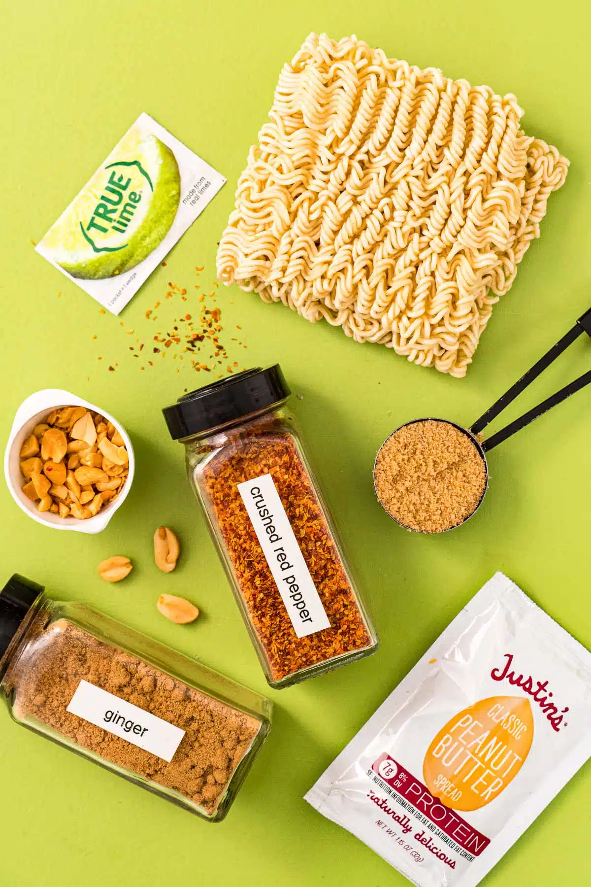Dried ramen noodles, brown sugar, spice jars, peanuts, peanut butter packet, and true lime packet.