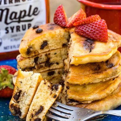 A stack of chocolate chip pancakes with strawberries on top