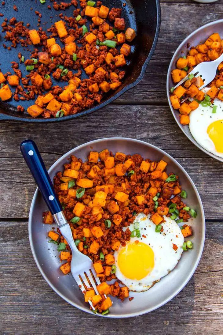 Sweet potato and chorizo hash with an egg on a plate.
