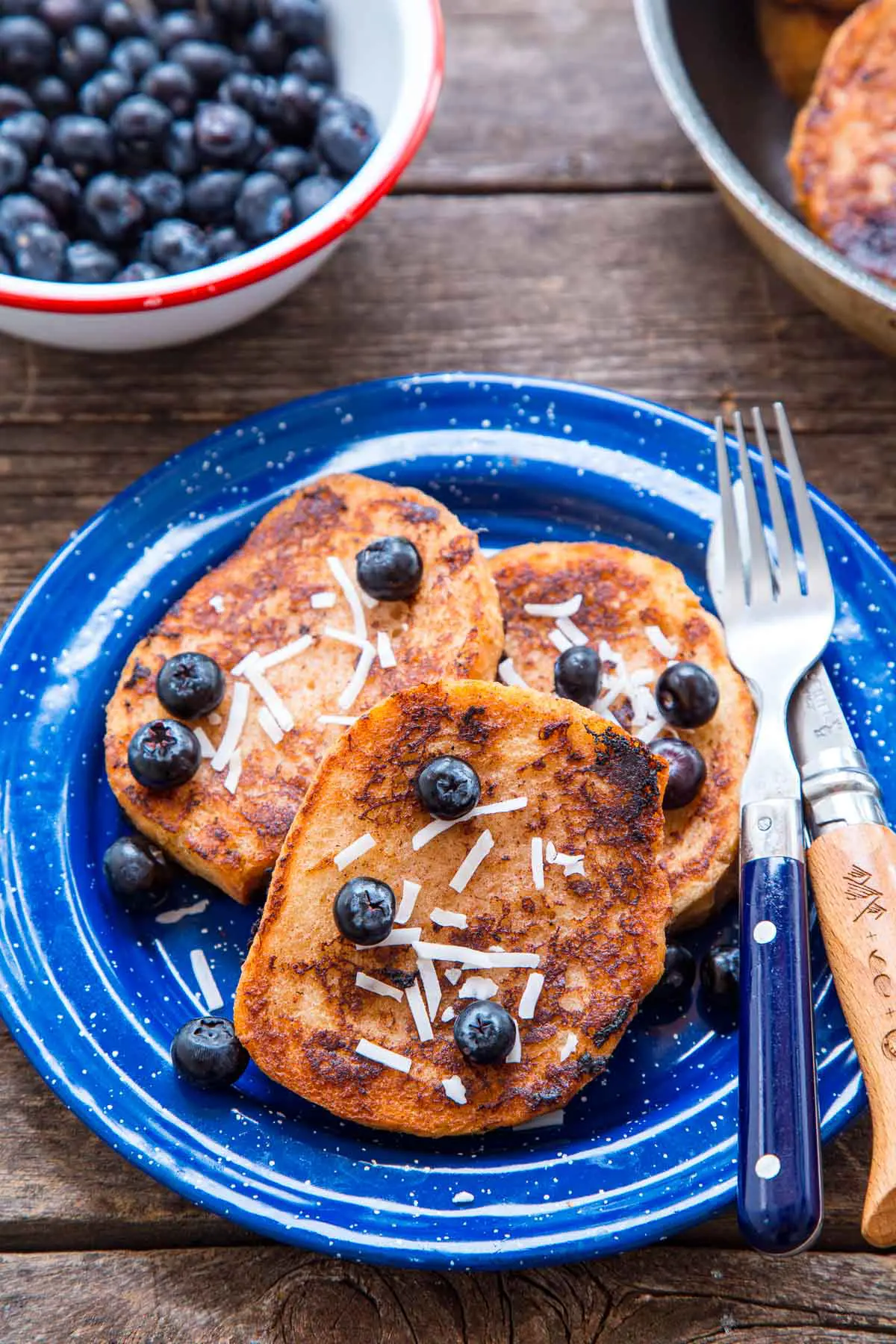Three slices of French toast with blueberries on a blue plate