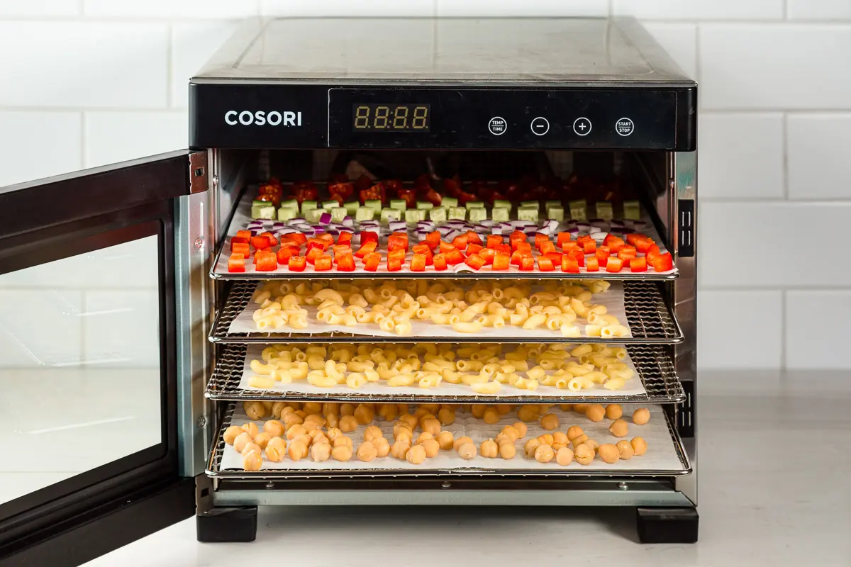 A dehydrator with the door open to show trays of food