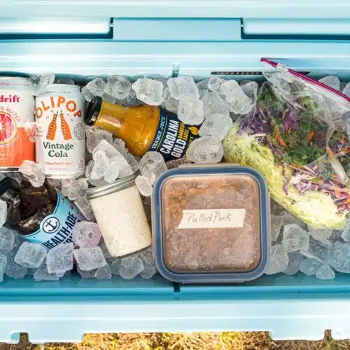 A cooler filled with ice, coleslaw components, and other items.