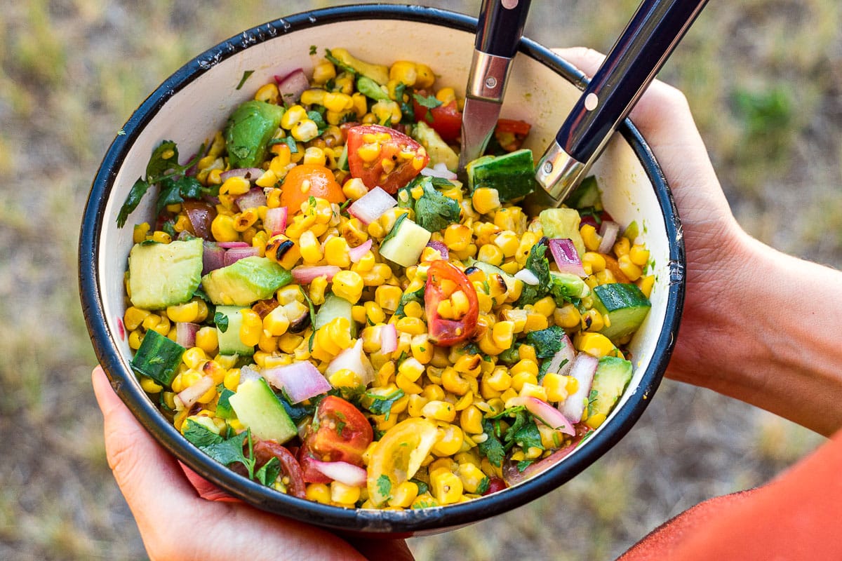 Hands holding a bowl of corn salad