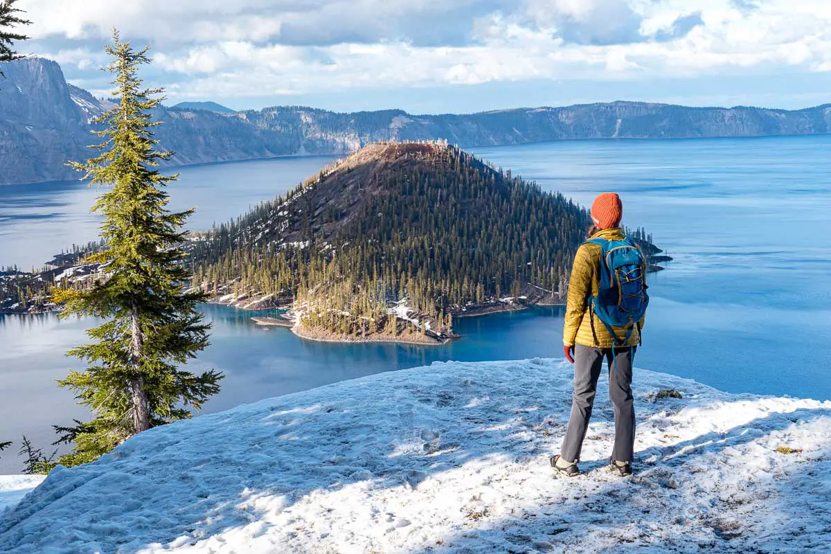 Megan standing on a snowy trail looking out at Wizard Island in Crater Lake