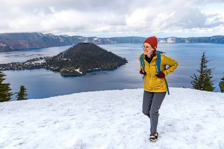 Megan walking on a snowy trail with Wizard Island in the background