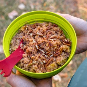 Overhead view of Megan holding a green backpacking bowl full of apple quinoa porridge