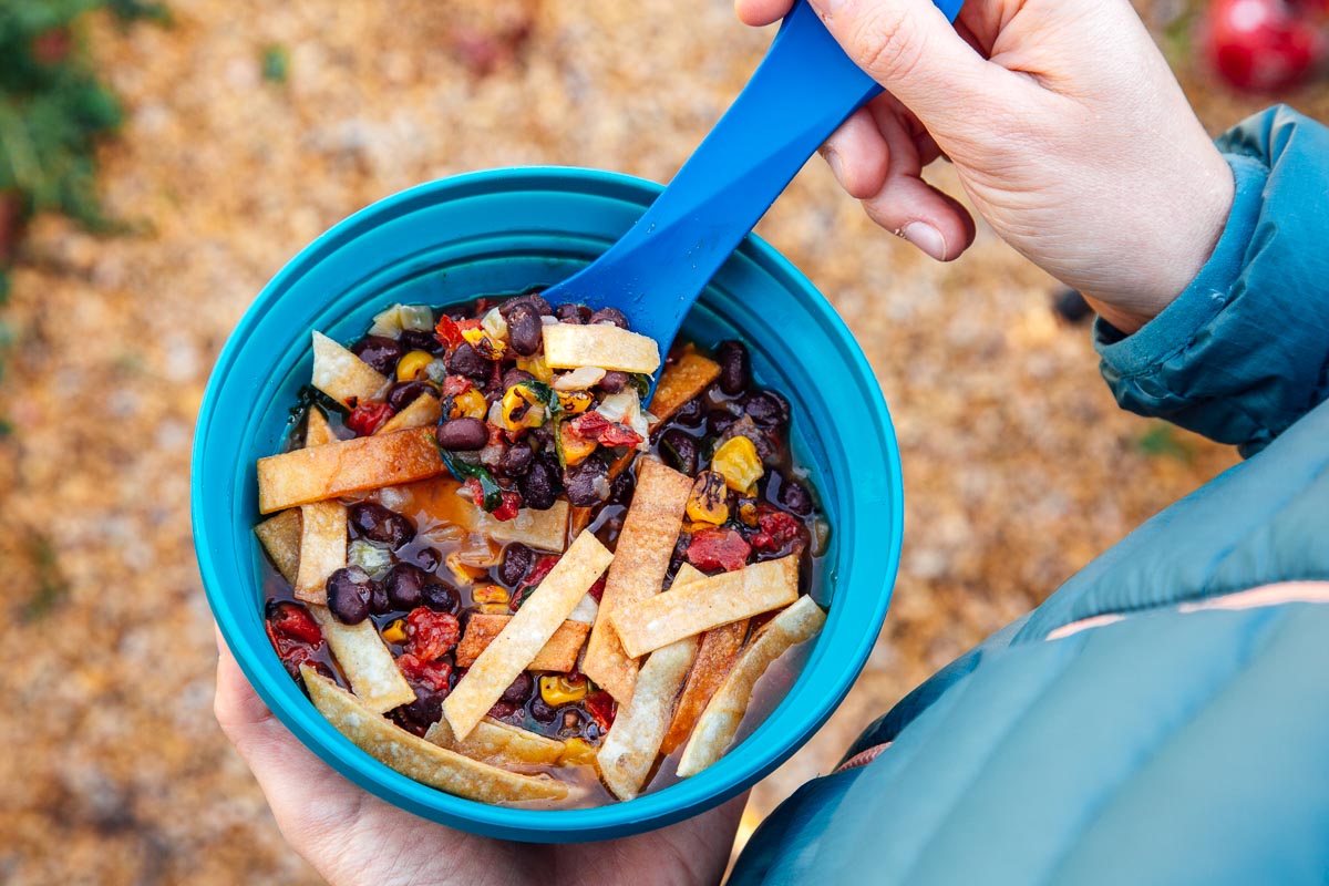 Megan holding a blue bowl of dehydrated tortilla soup