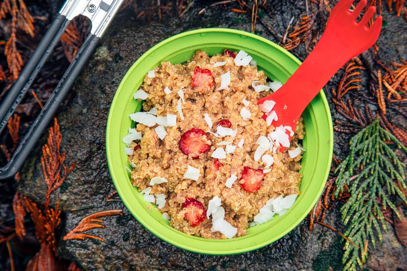 Strawberries and cream quinoa porridge in a bowl on a rock