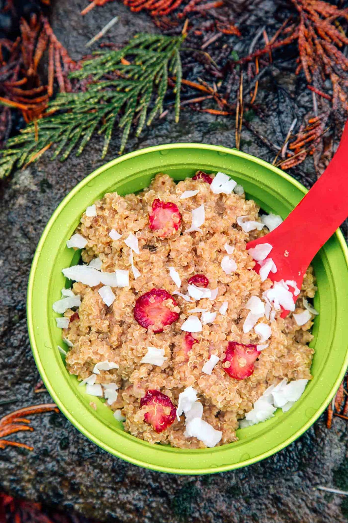Strawberries and cream quinoa porridge in a bowl on a rock