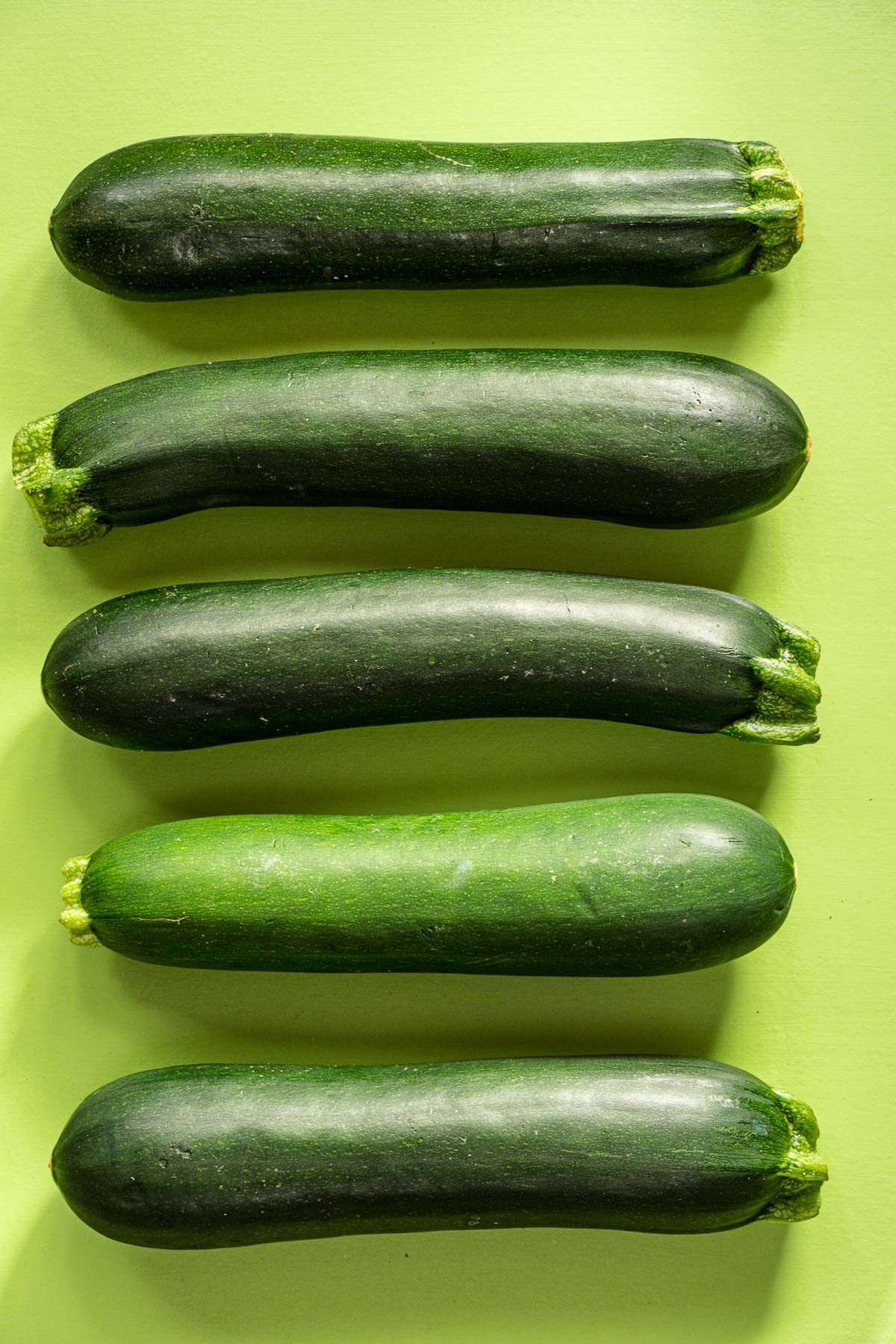Five zucchini on a green surface