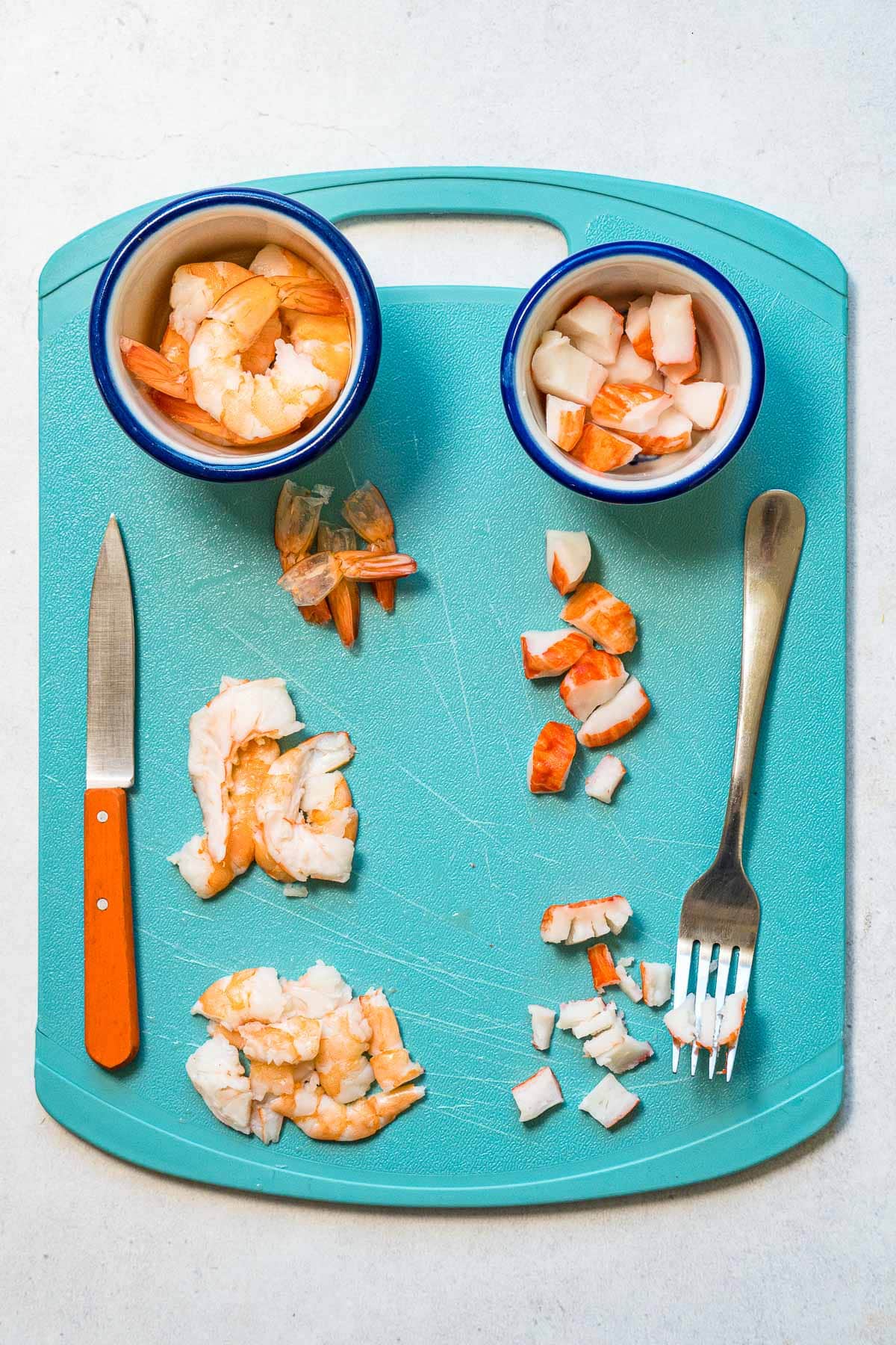 Shrimp and imitation crab on a blue cutting board