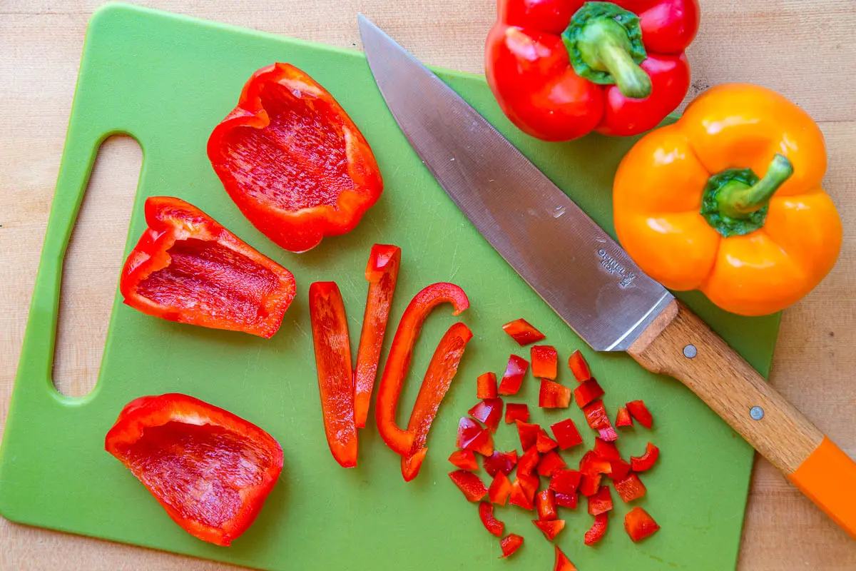 Sliced red bell peppers on a green cutting board