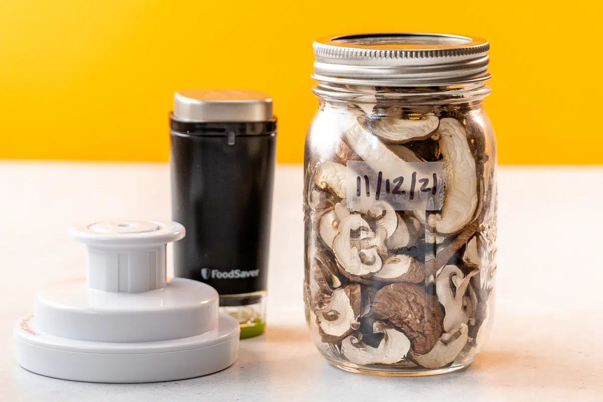 Dehydrated mushrooms in a jar next to vacuum sealing accessories