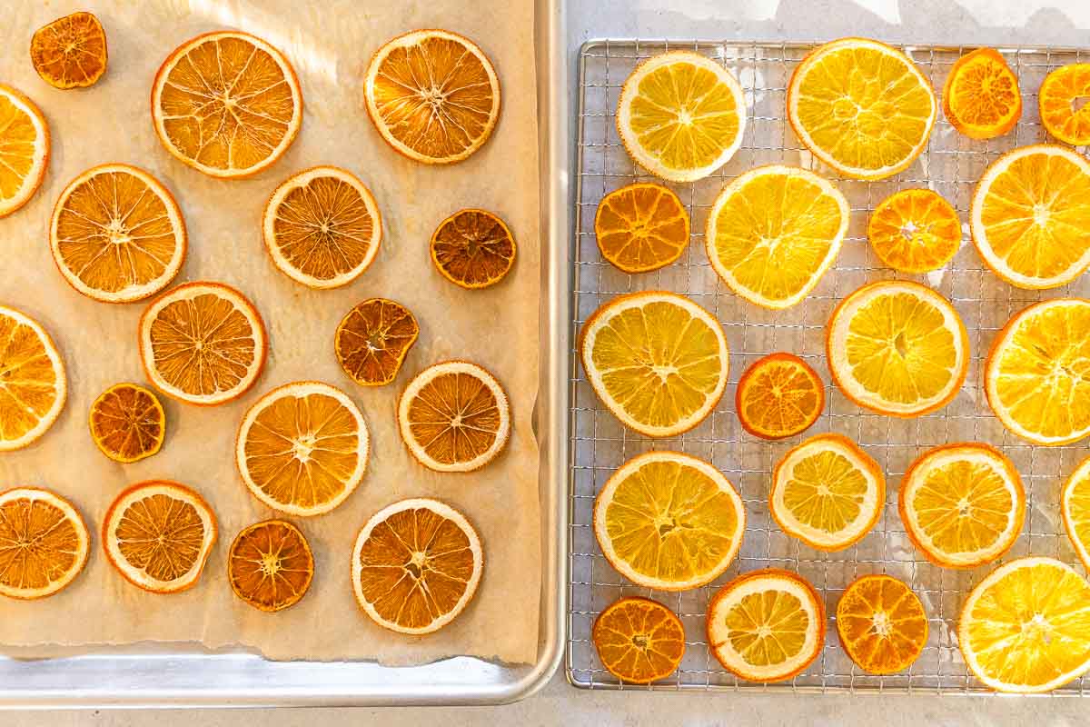 Two trays of dried orange slices: left tray on paper with darker slices, right tray on wire rack with brighter, even-colored slices.