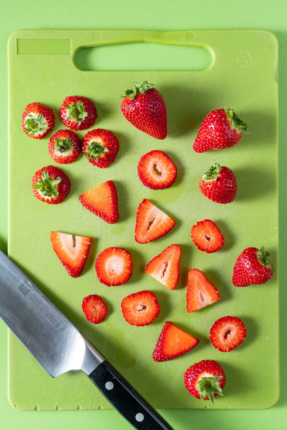 Strawberries sliced on a green cutting board