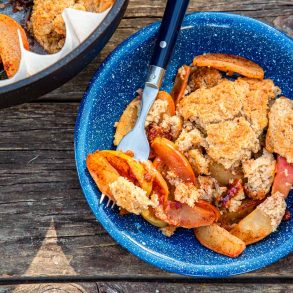 Apple cobbler in a blue bowl next to a Dutch oven