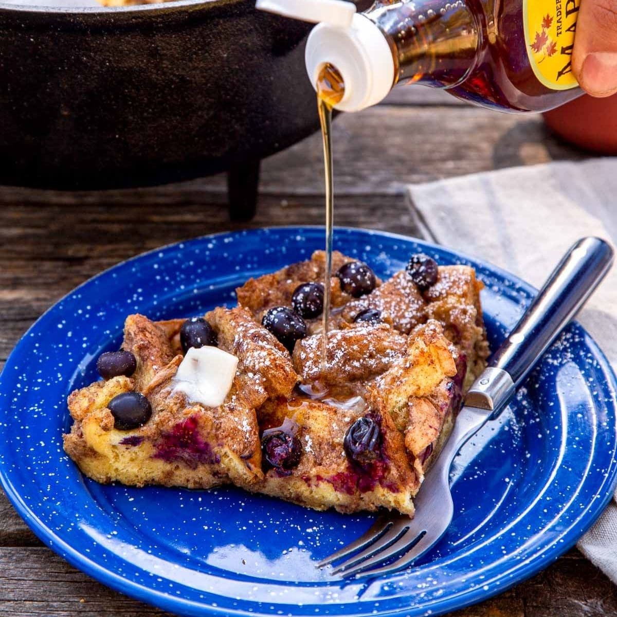 Maple syrup being drizzled over a slice of baked French toast.