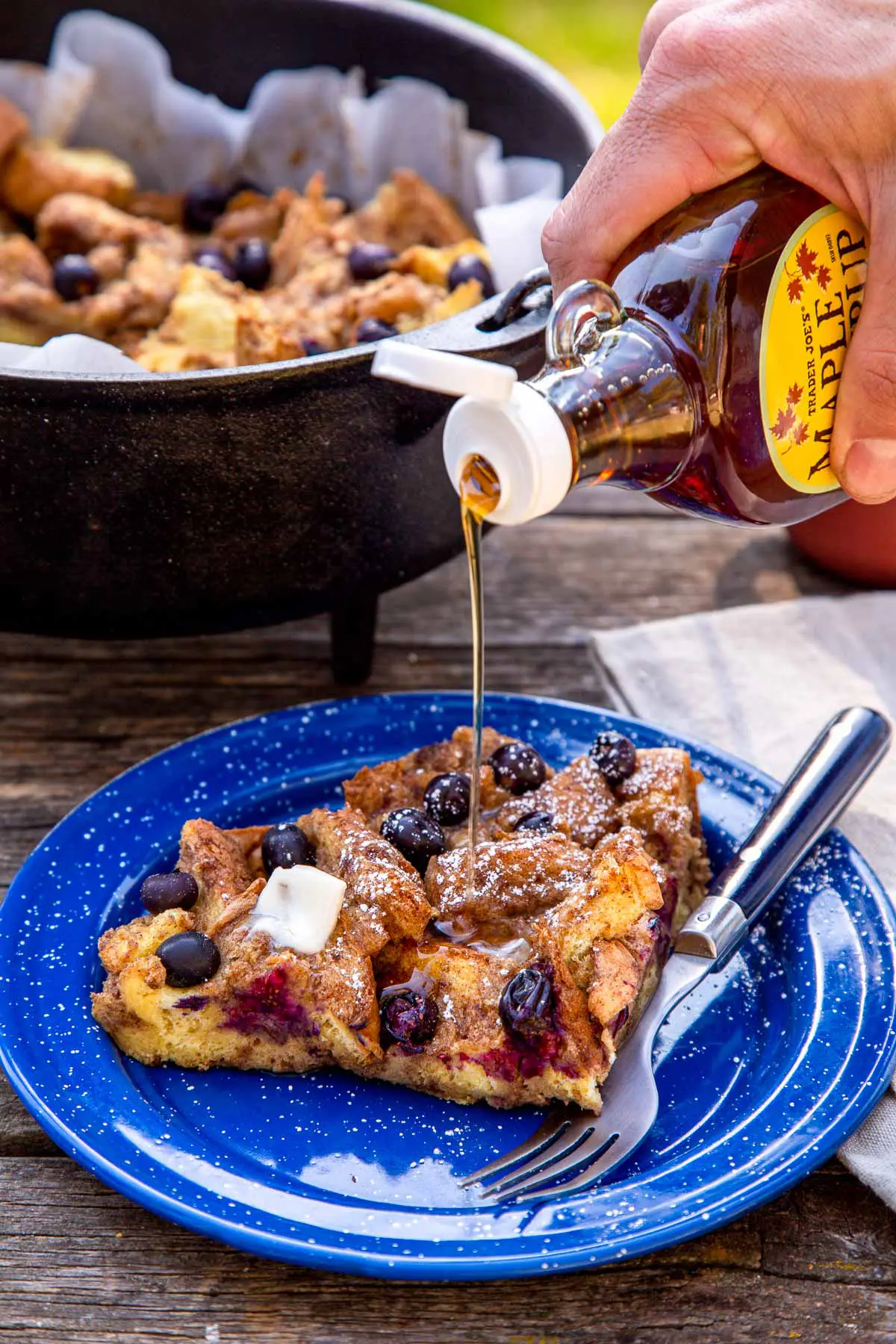 Maple syrup being drizzled over a slice of baked French toast.