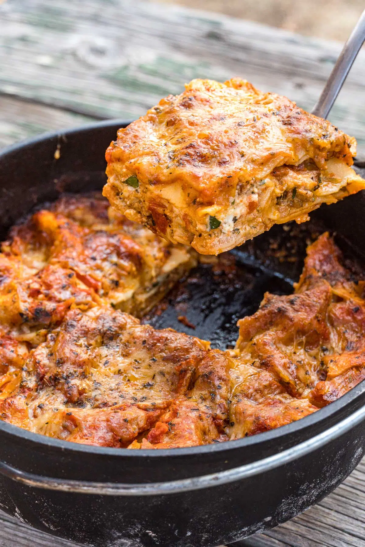 Lifting a slice of lasagna out of a Dutch oven.