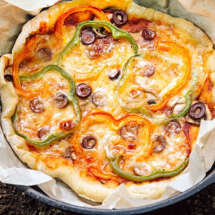 Pizza topped with cheese and bell peppers in a Dutch oven