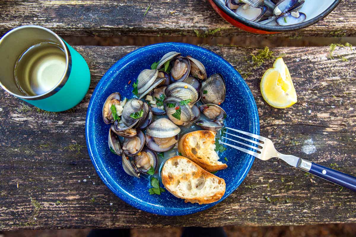 A bowl with steamed clams and grilled bread on a table