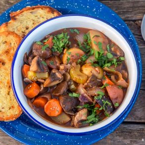 Vegetable stew in a blue and white bowl with grilled bread on the side