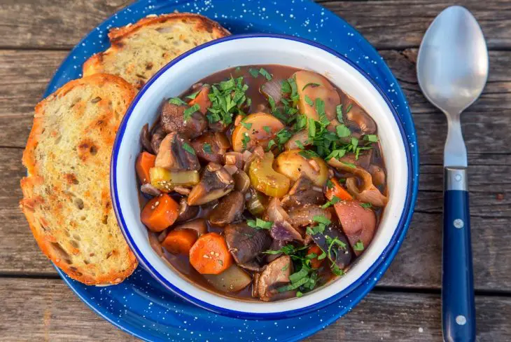 Vegetable stew in a blue and white bowl with grilled bread on the side