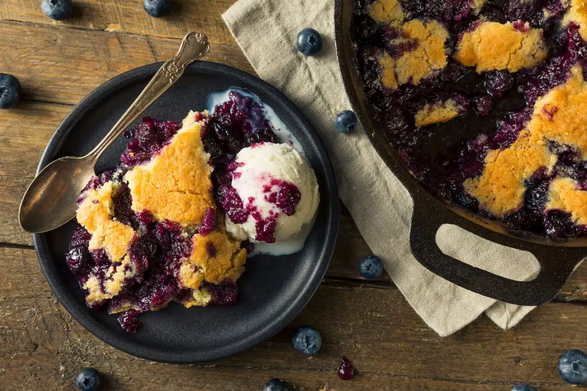 Berry cobbler on a plate next to cast iron.