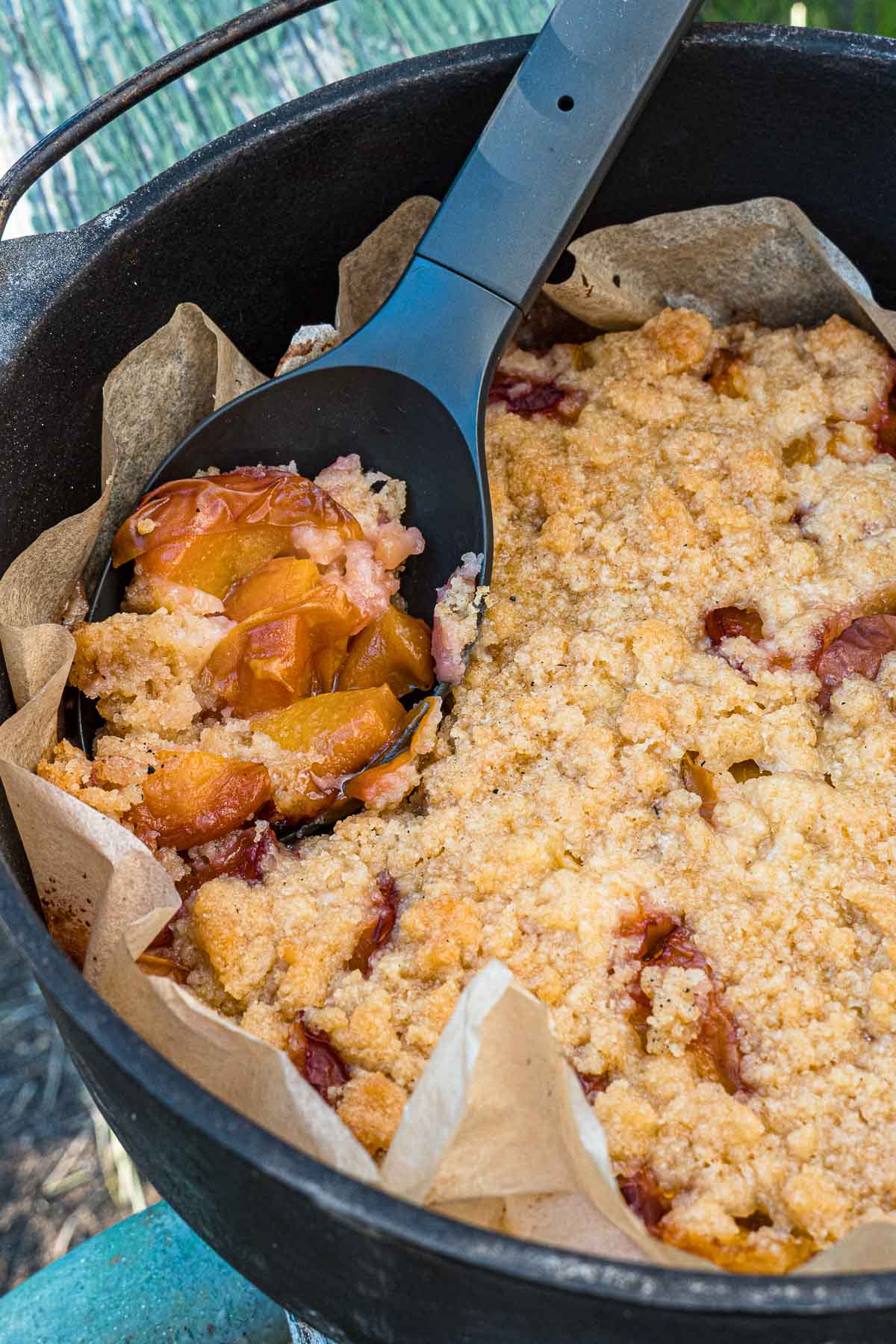 A large spoonful of peach cobbler resting in a dutch oven