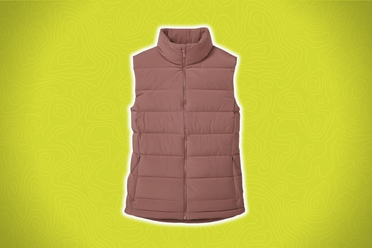 A mauve puffer vest with a high collar and zippered front lies on a bright yellow background with wavy line patterns.