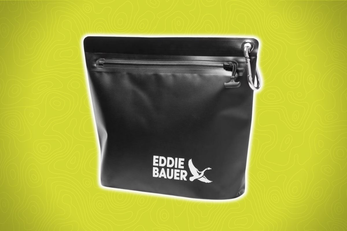 A black Eddie Bauer zippered pouch with a wrist strap and white logo sits on a yellow background with faint topographic lines.