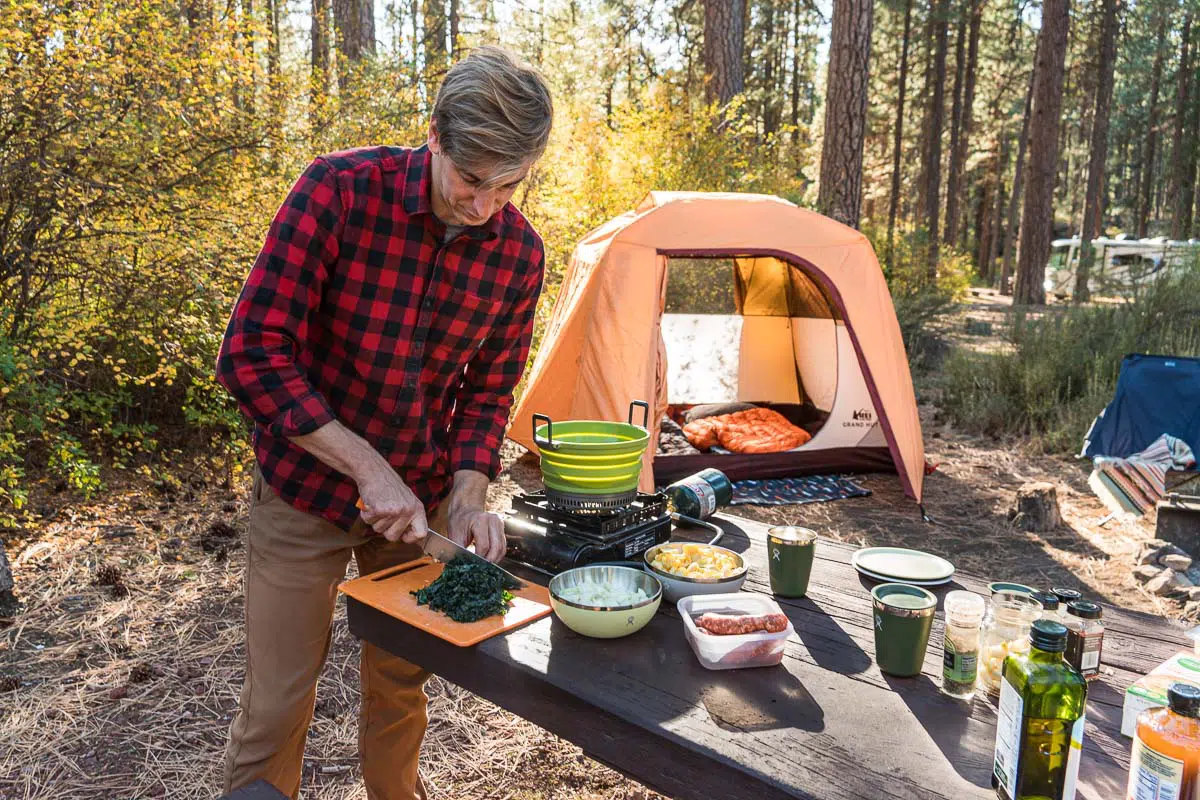 Michael cooking at a camp table with a tent in the background
