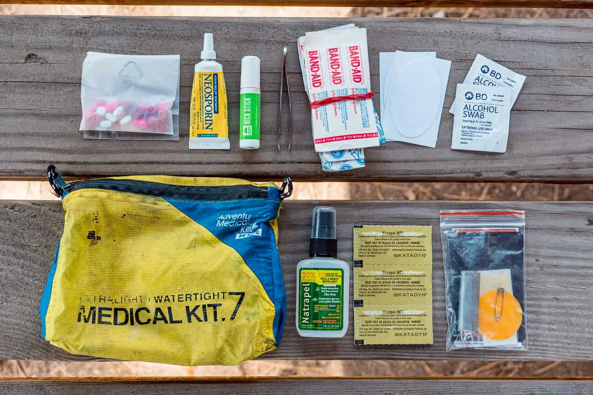 Contents of a hiking first aid kit laid out on a wood background