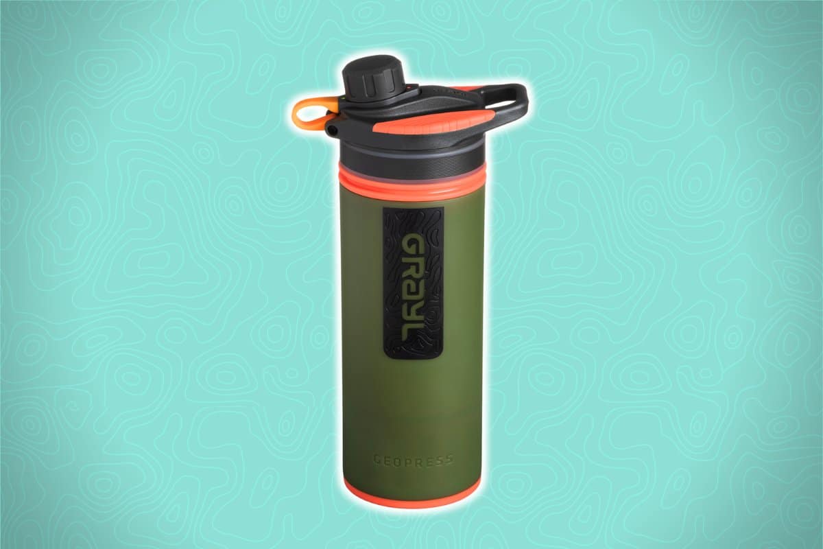 A green and black Geopress water filtration bottle with an orange handle, set against a light turquoise background featuring a subtle contour map pattern.