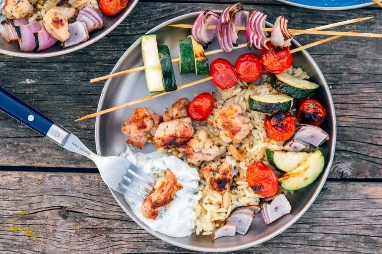 Chicken and vegetable skewers on a silver camping plate