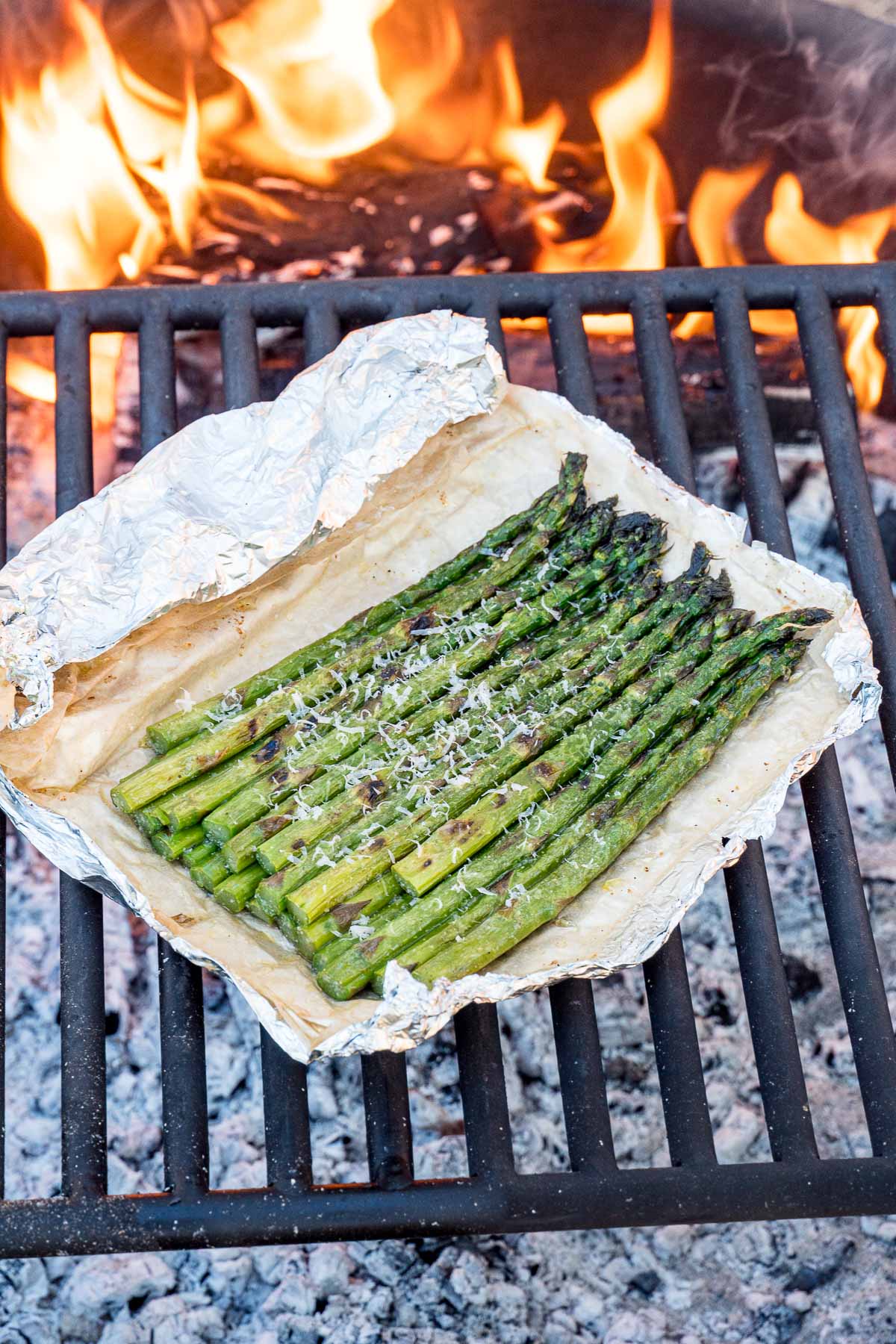 Grilled asparagus in a foil packet on a campfire