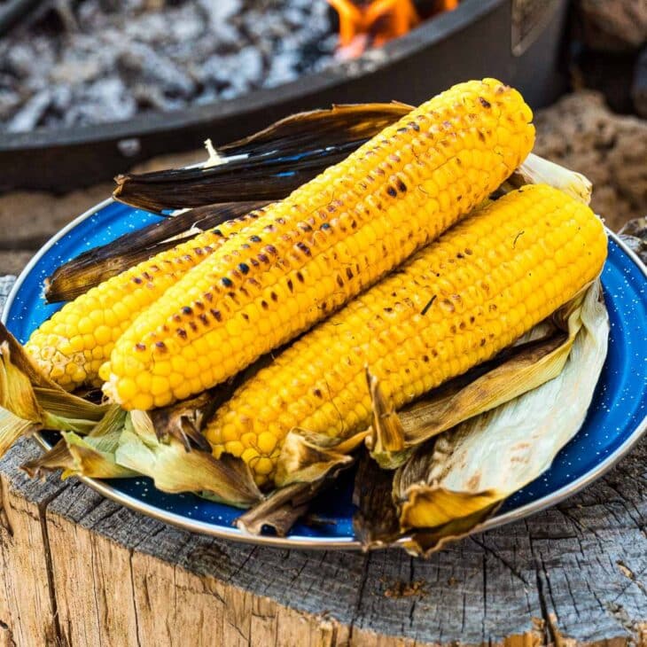 Grilled corn on the cob stacked on a blue plate.