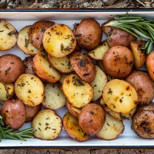 Grilled potatoes in a baking dish garnished with rosemary