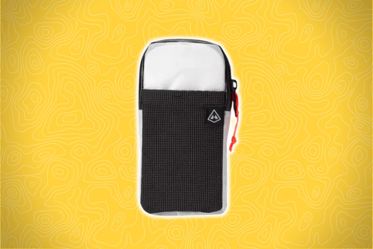 A small black and white zippered pouch with a red zipper pull sits on a yellow background with wavy abstract lines.